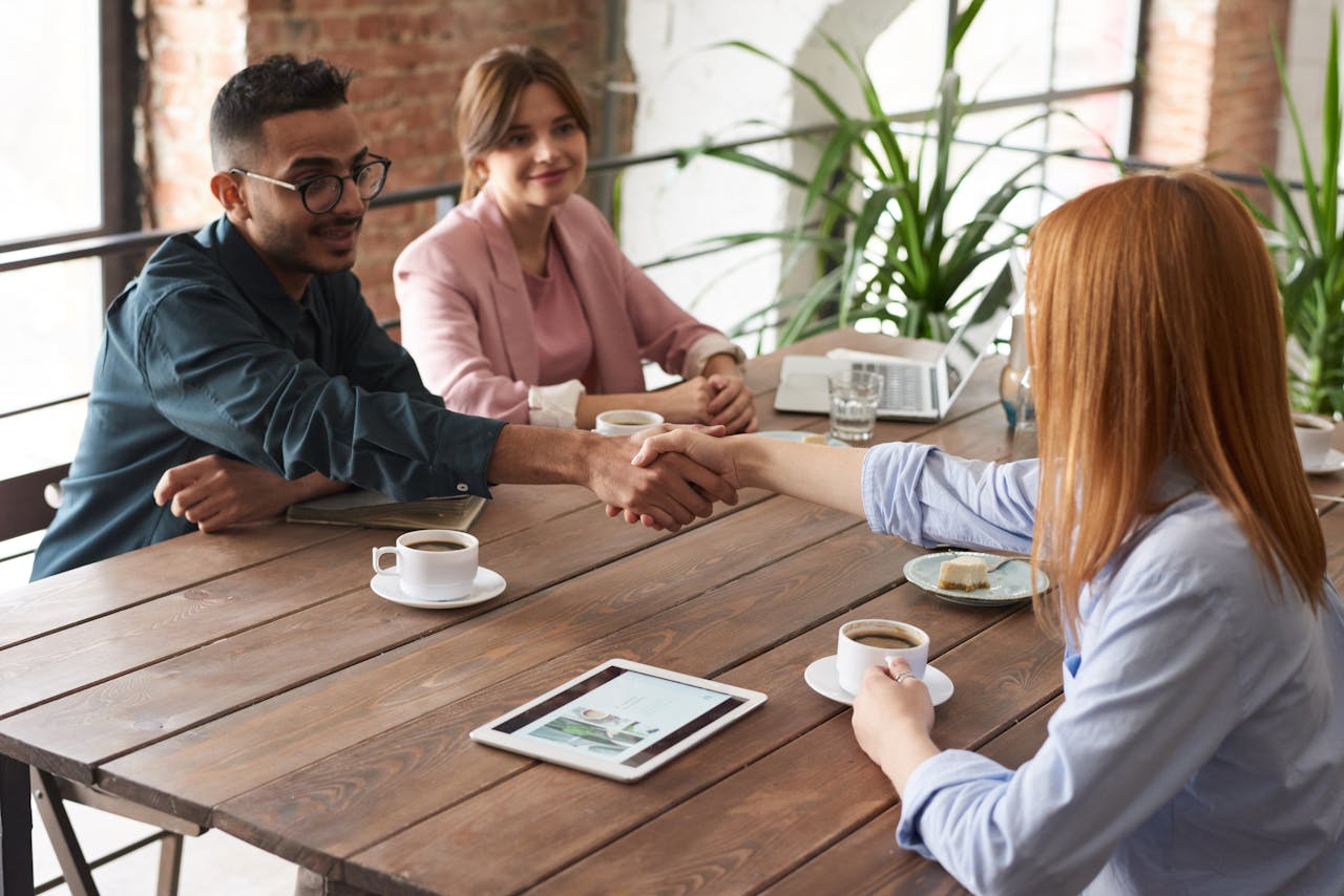 Colleagues collaborate over coffee during a positive business meeting with a handshake.