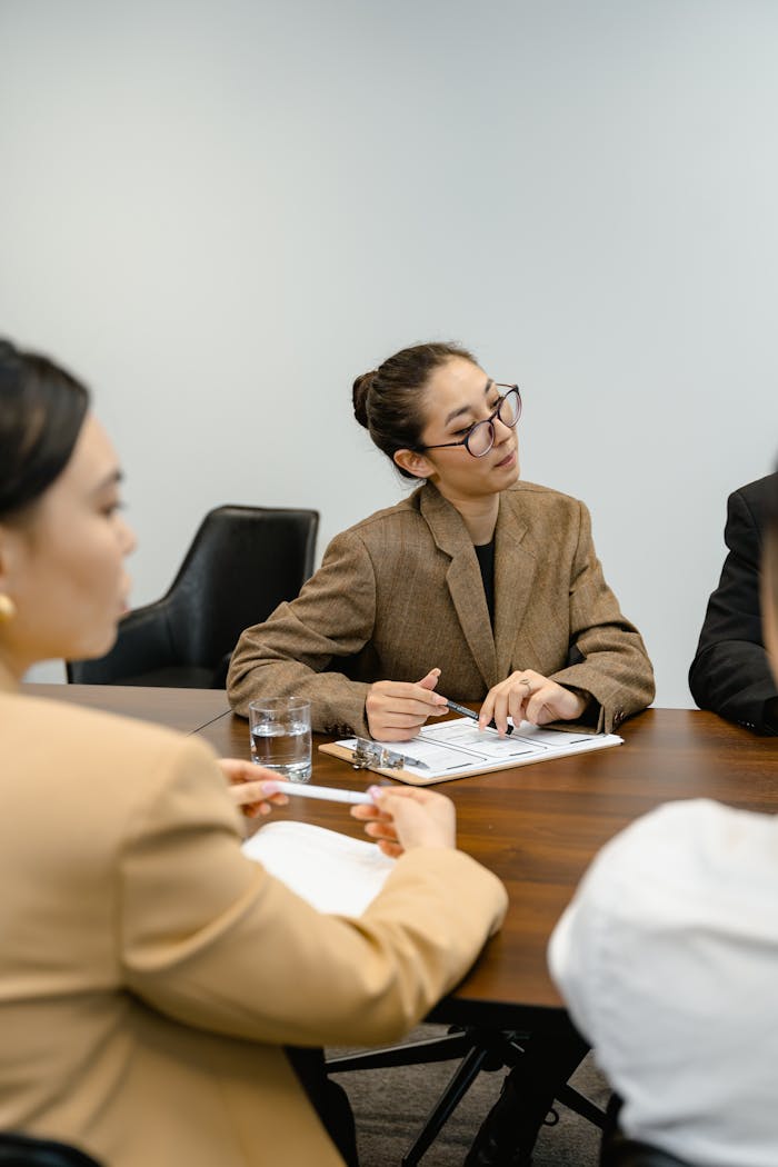 Three business professionals in a collaborative meeting at a wooden table in an office setting.